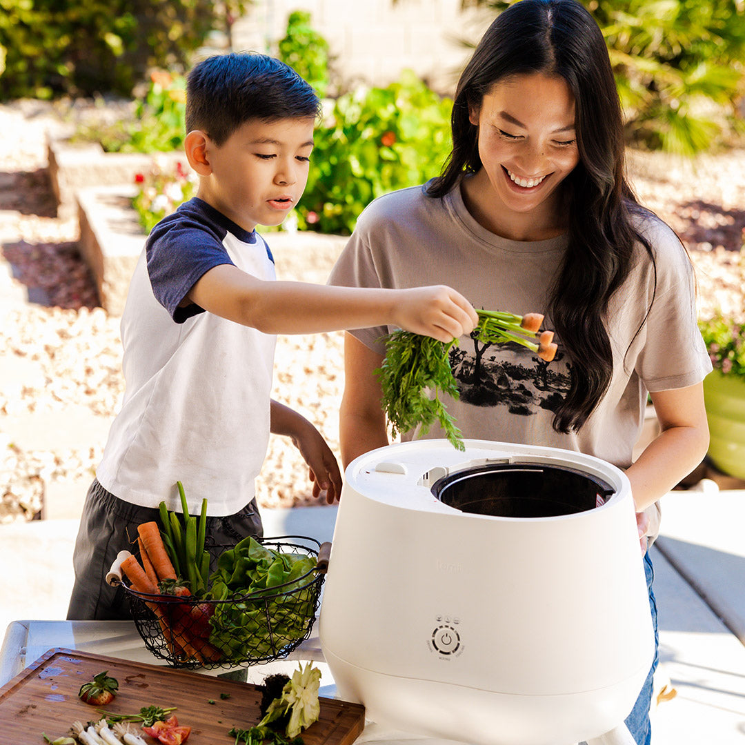 Woman and boy putting scraps in Lomi composter
